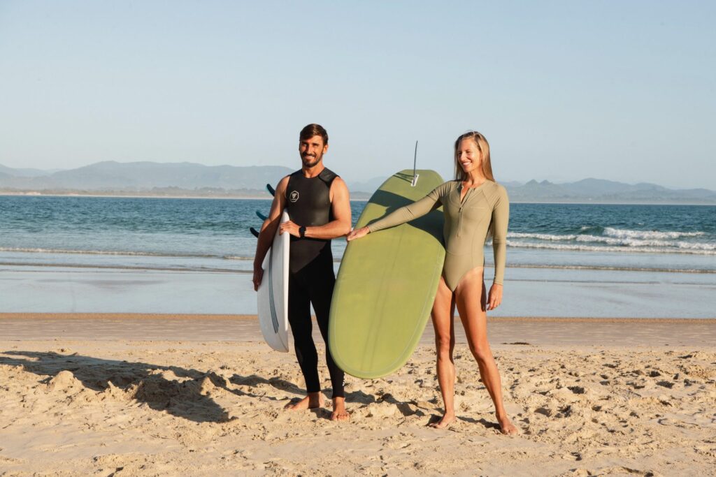Waluaa co-founders Vickie Mogensen and Sergio Bryksa with surfboards on the beach near Byron Bay